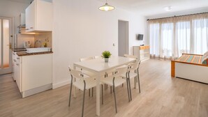 Une pièce moderne et bien éclairée, comprenant une table et des chaises, un petit coin cuisine et un lit avec vue.