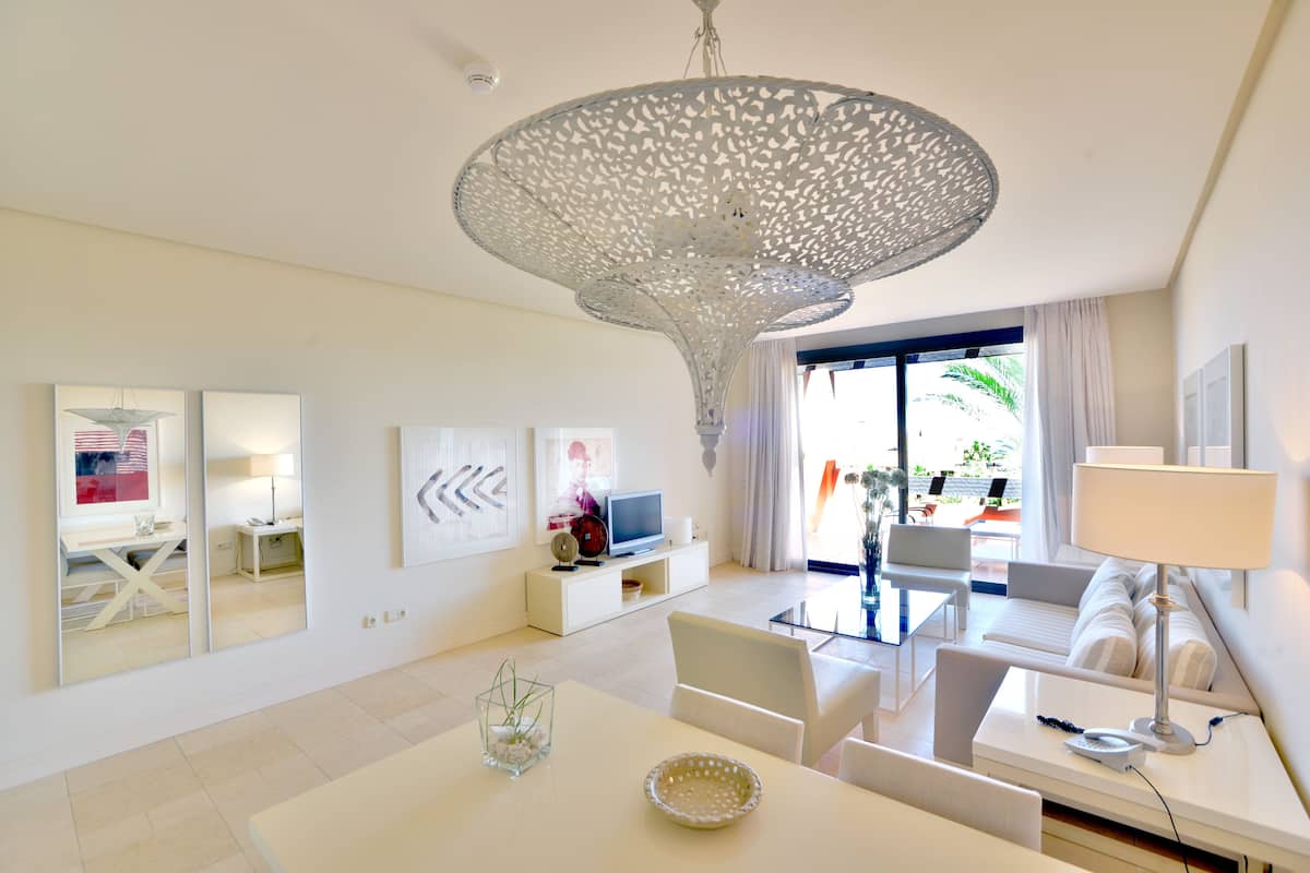 A modern living room with a white sofa, a dining table, and a unique ceiling light fixture.