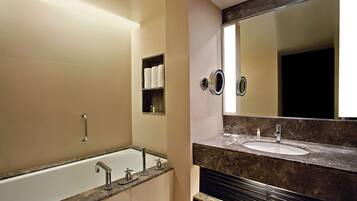 A modern bathroom with a bathtub, a vanity with a sink, and a large mirror.