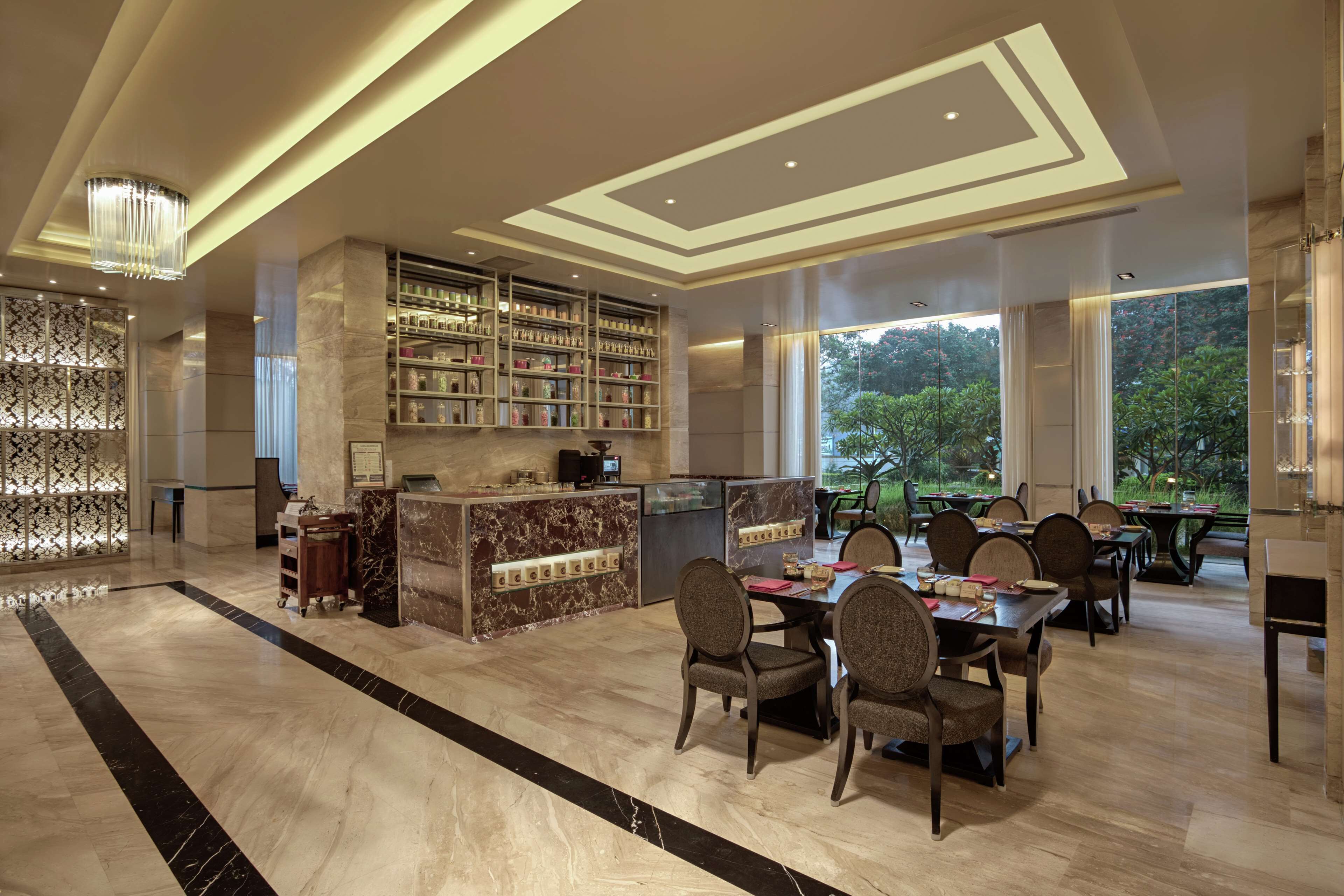 A spacious lobby with a marble floor, a reception desk, a bar area with shelves, and a dining area with tables and chairs.