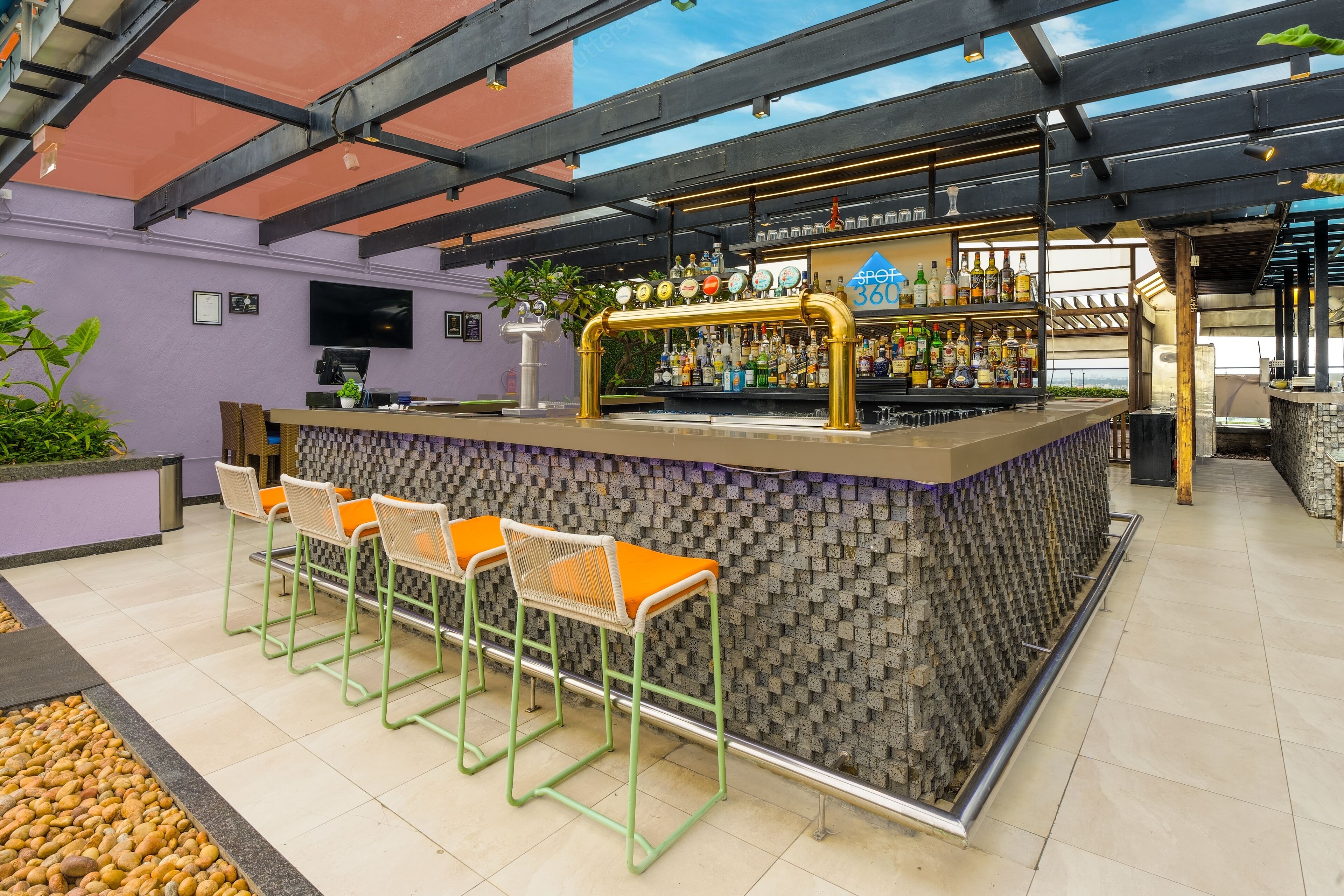 A bar area with a counter, stools, and a variety of bottles.