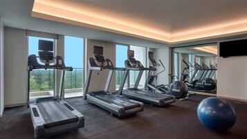 A gym with treadmills, exercise balls, and a large window offering a view of the outdoors.