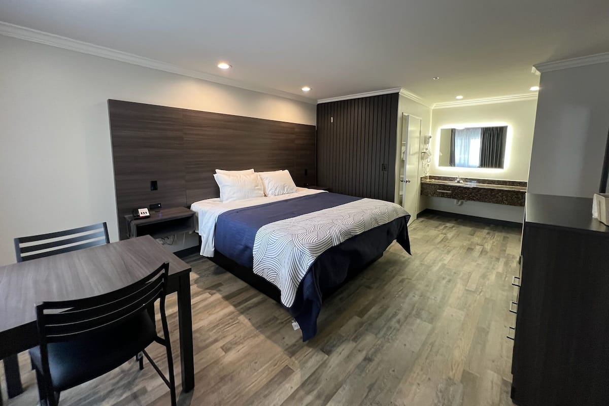 A modern hotel room with a large bed, a desk, and a bathroom.