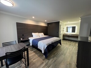 Una habitación de hotel moderna con una cama grande, un escritorio y un baño.