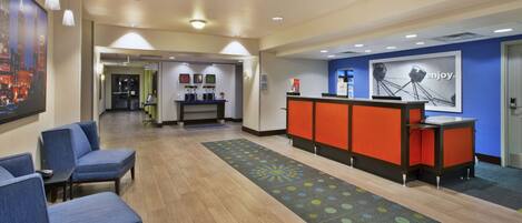 A hotel reception area with a reception desk, seating area, and a coffee station.