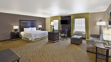 Ein Hotelzimmer mit Bett, Schreibtisch, Stuhl und Hocker.