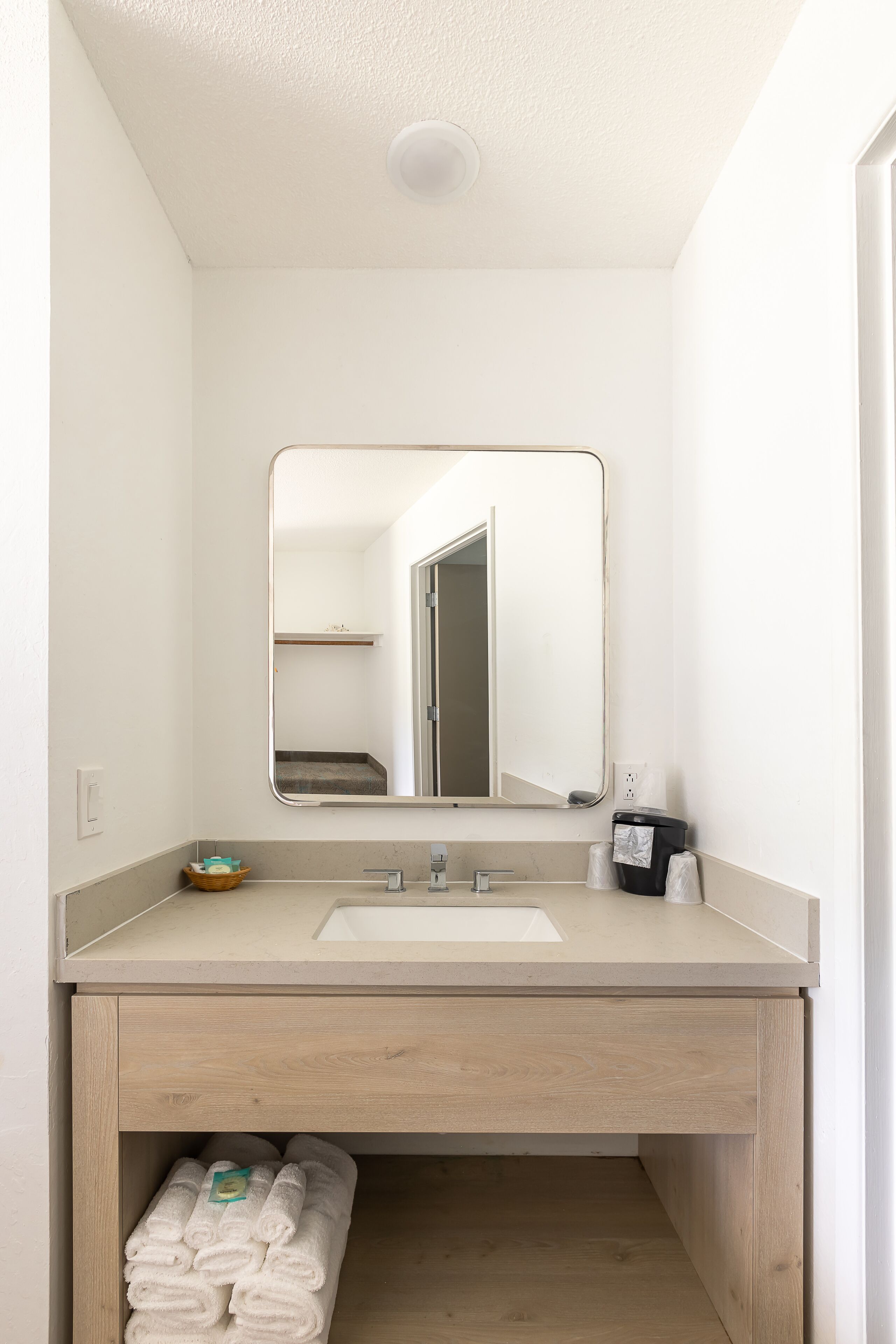A bathroom with a sink, mirror, and towel storage.