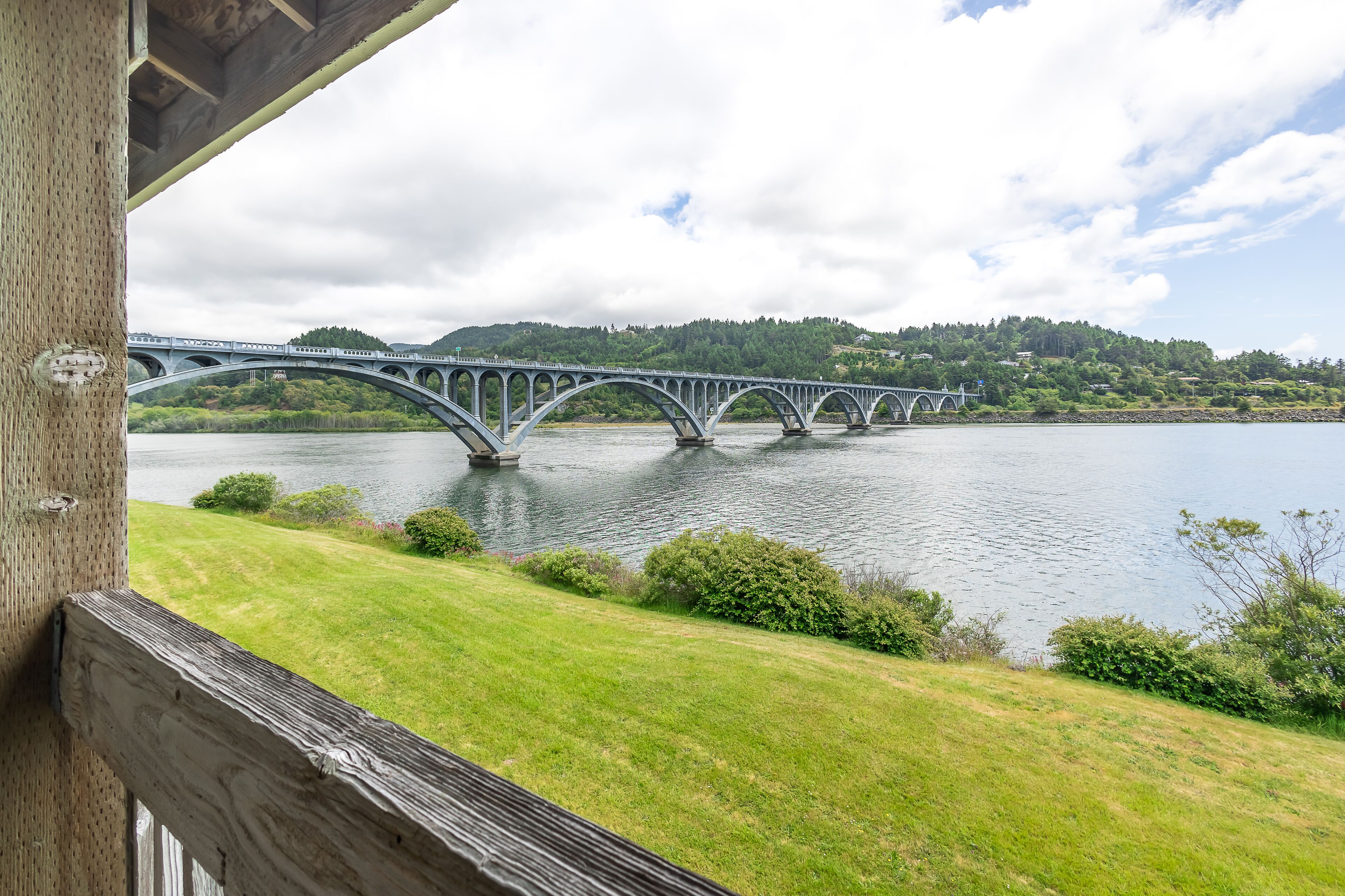 Vista de un puente sobre el agua, con una zona verde al frente.