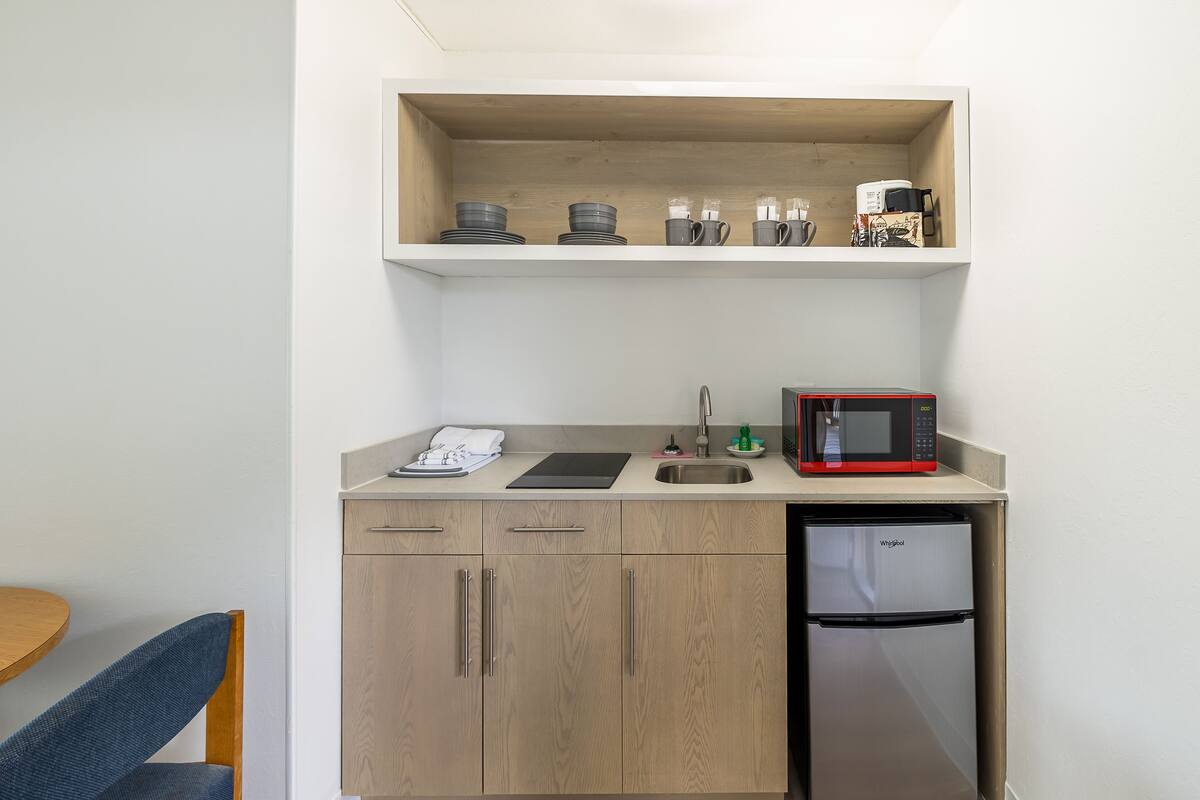 A compact kitchenette with a microwave, a sink, and a small refrigerator.