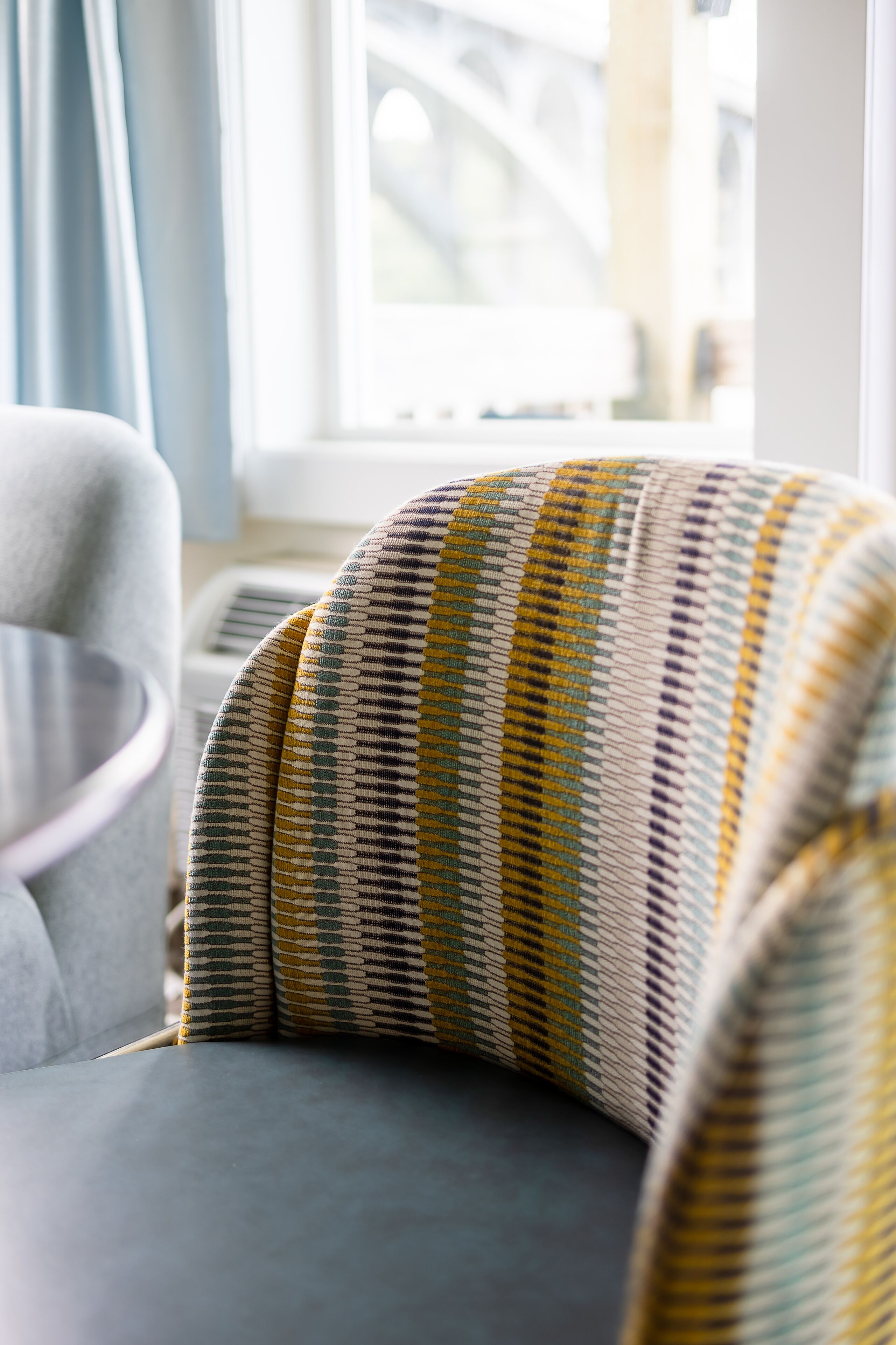 A corner of a room with a grey sofa and a patterned cushion.