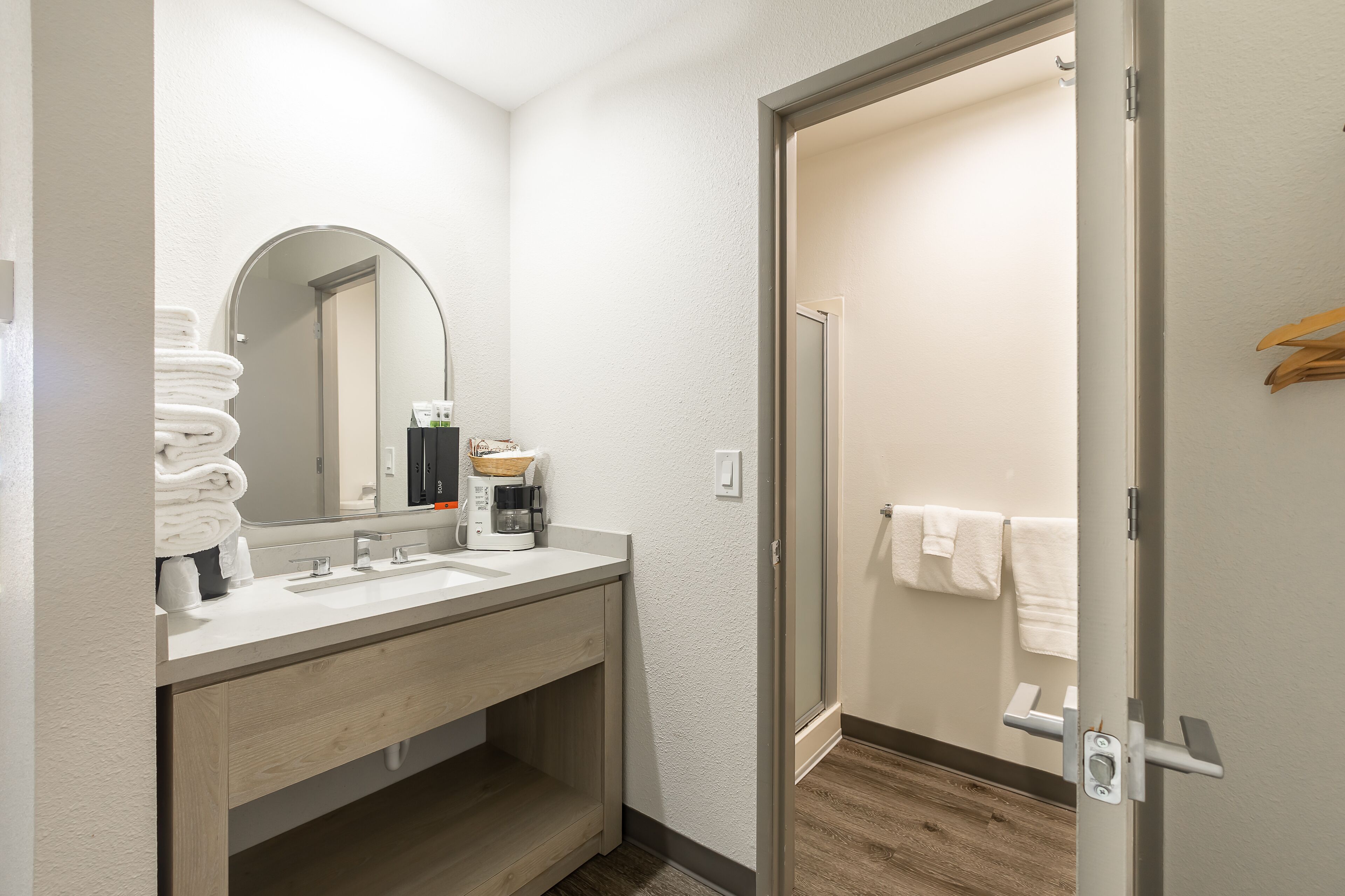 Un baño moderno con lavamanos, espejo y toallero.