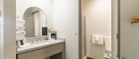 Un baño moderno con lavamanos, espejo y toallero.