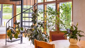 A spiral staircase leading to a balcony with large windows, wooden flooring, and a table with chairs and potted plants. - Jot's Resort (Gold Beach)