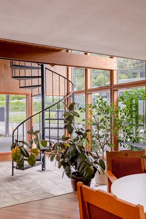 A spiral staircase with a view of the outside. There are potted plants and a wooden chair in the room. - Jot's Resort (Gold Beach)