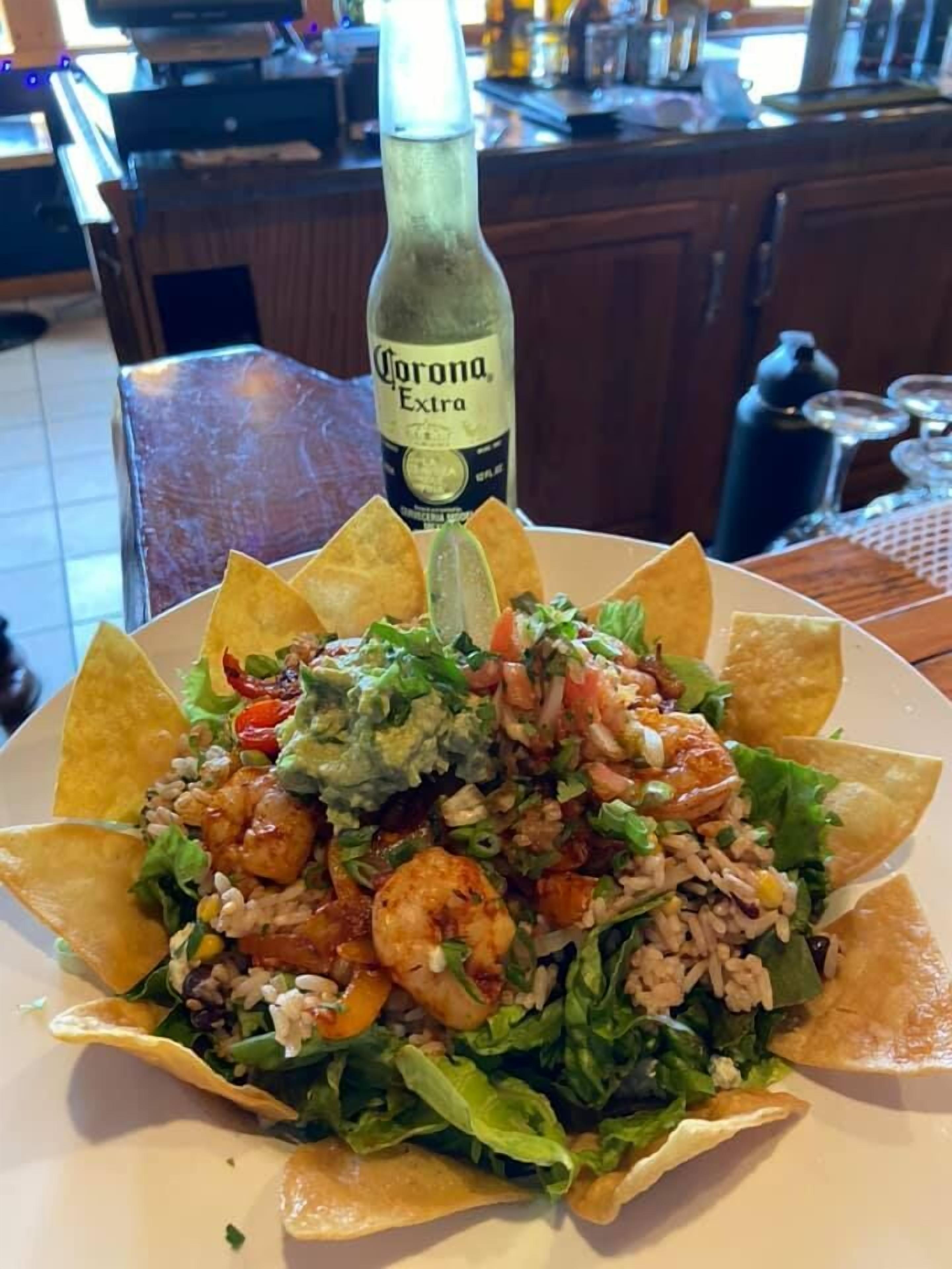 A plate of shrimp taco salad with a bottle of Corona Extra beer.