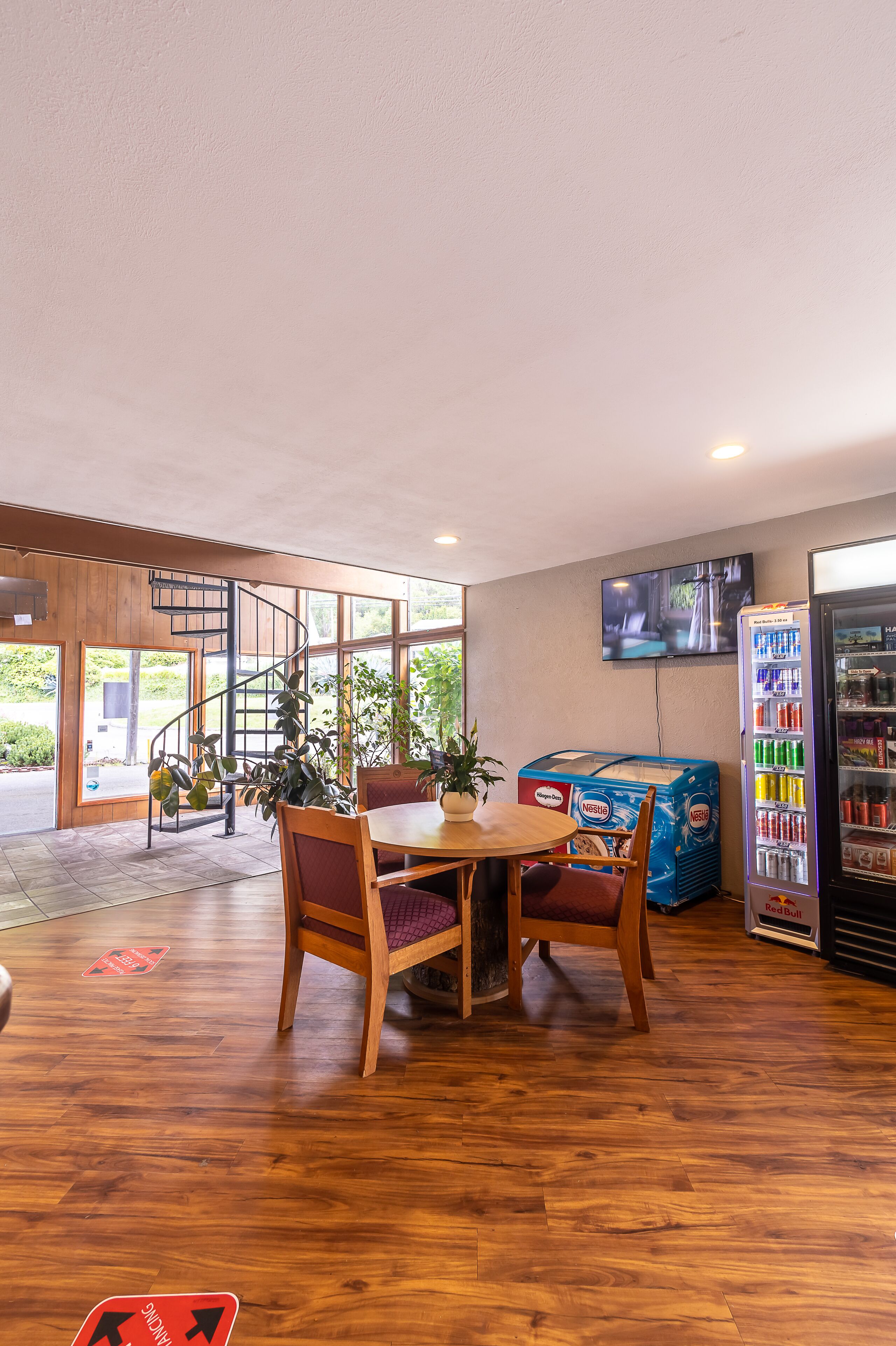 Un restaurante con interior de madera, una escalera de caracol, un televisor montado en la pared y una máquina expendedora.