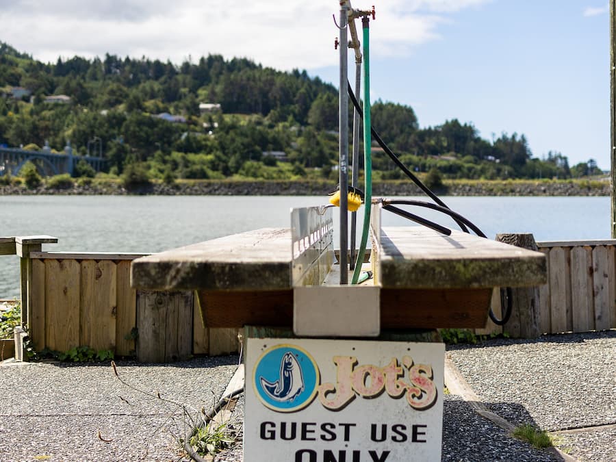 Señal para un servicio de alquiler de botes, con vista a un lago y un bosque al fondo.