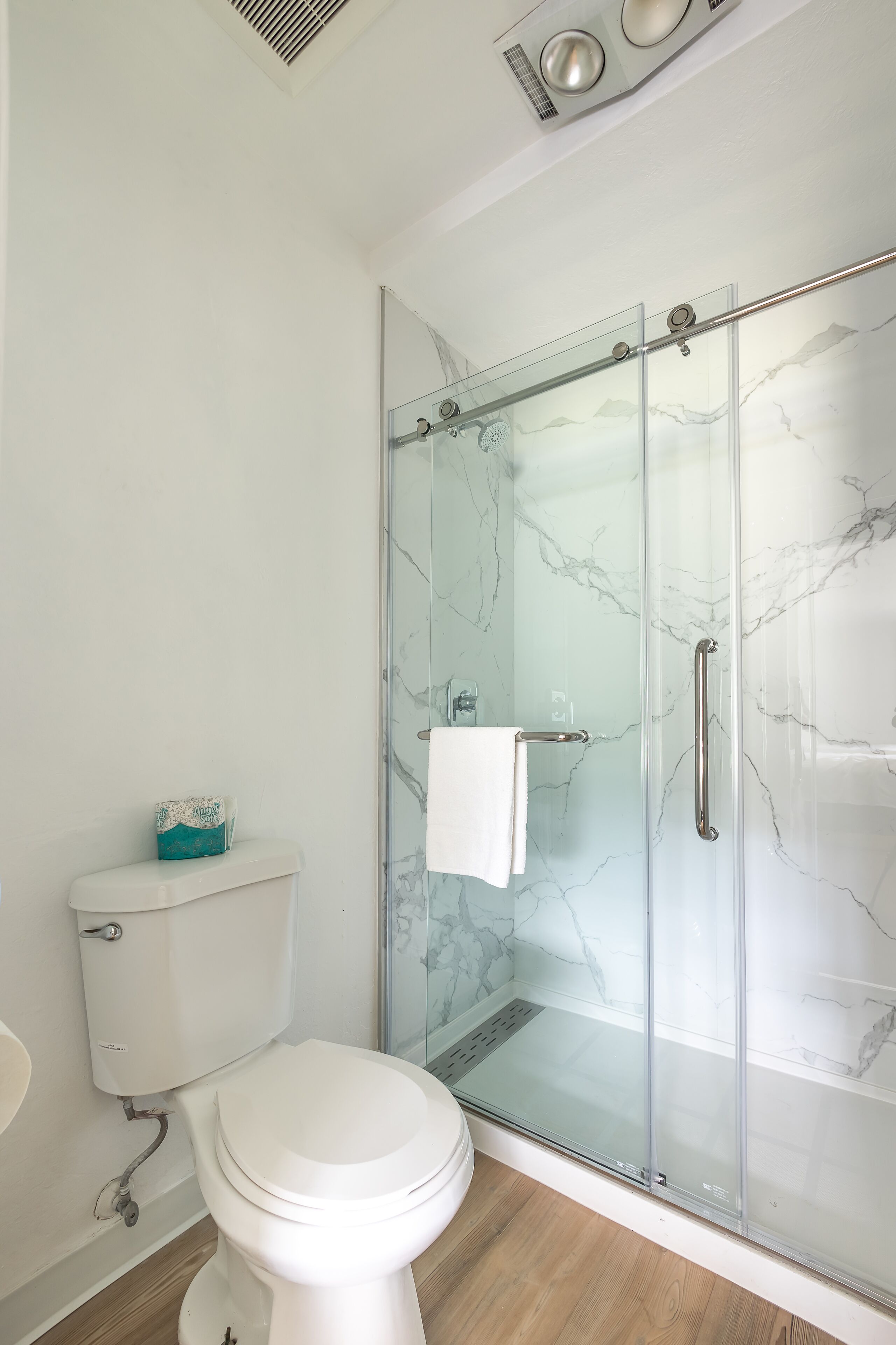 Un baño moderno con cabina de ducha de vidrio, inodoro blanco y salpicadero de mármol.