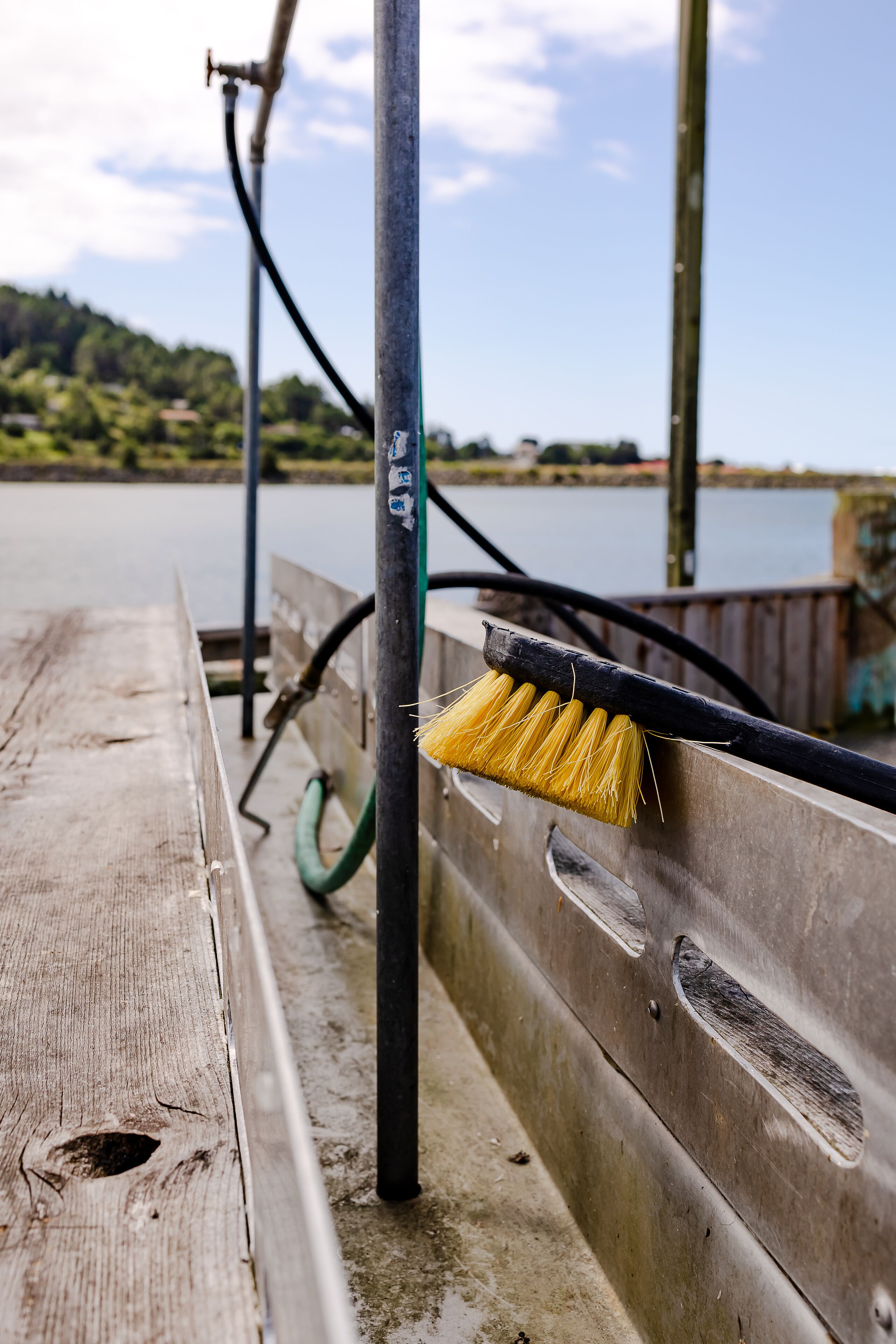 A wooden dock with a metal railing and a brush hanging on it.