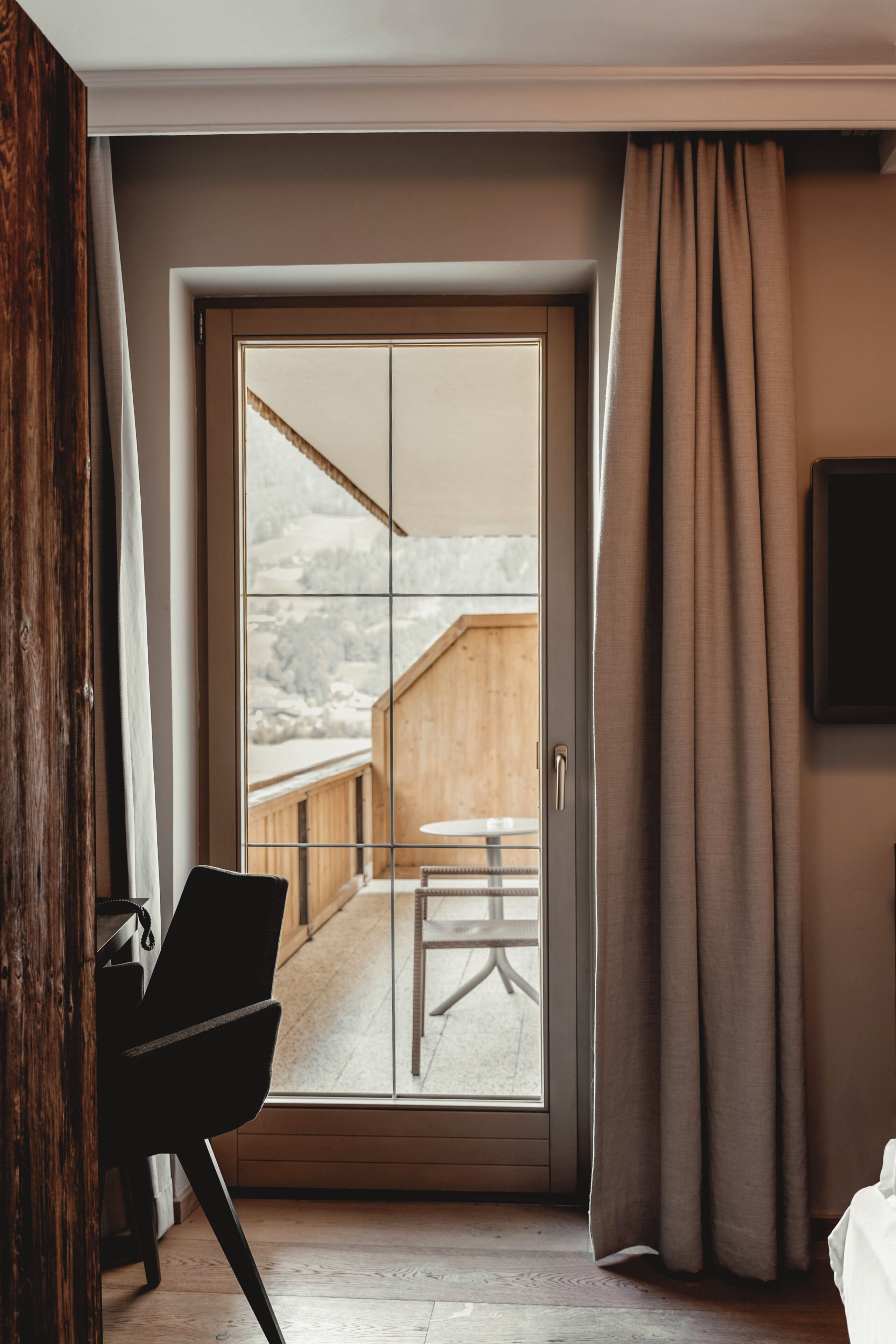 Ein Hotelzimmer mit einer Schiebetür zu einem Außenbereich mit einer Holzterrasse und einem Tisch.