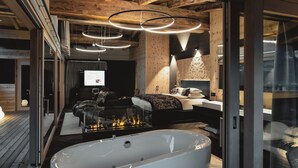 Un baño moderno con una bañera independiente, vigas de madera en el techo e iluminación colgante.