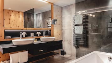 A modern bathroom with a large mirror, two sinks, a bathtub, and a glass-enclosed shower.