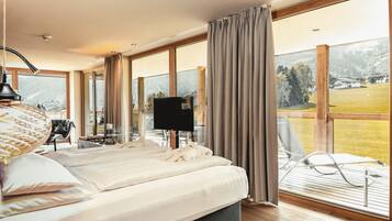 Ein Schlafzimmer mit einem großen Bett, einem Fernseher und einem Balkon mit Blick auf die Landschaft.