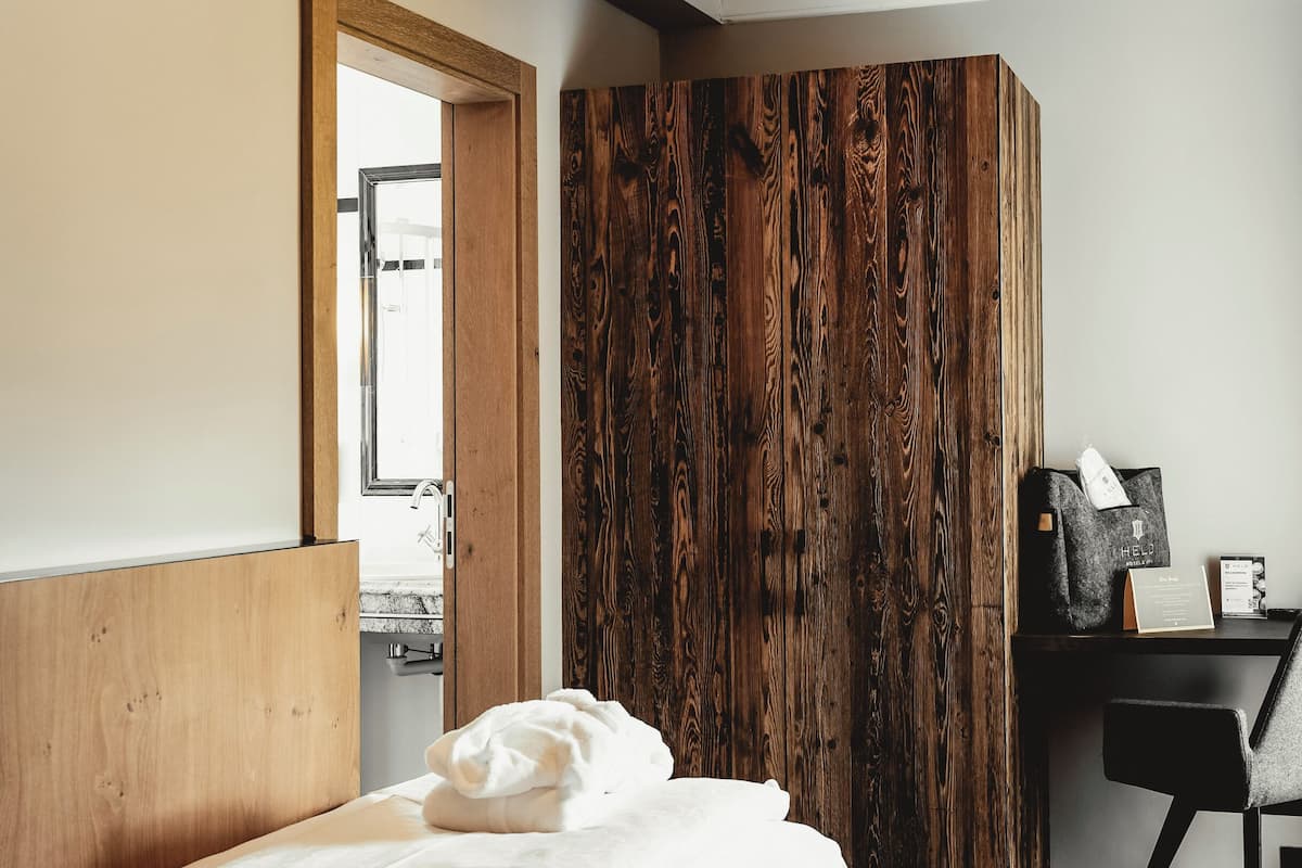 A modern bedroom with a wooden headboard, a desk with a chair, and a large mirror.