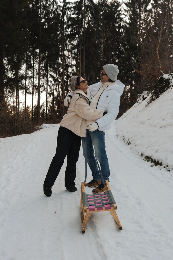 A snowy outdoor scene with a wooden sled and two people.