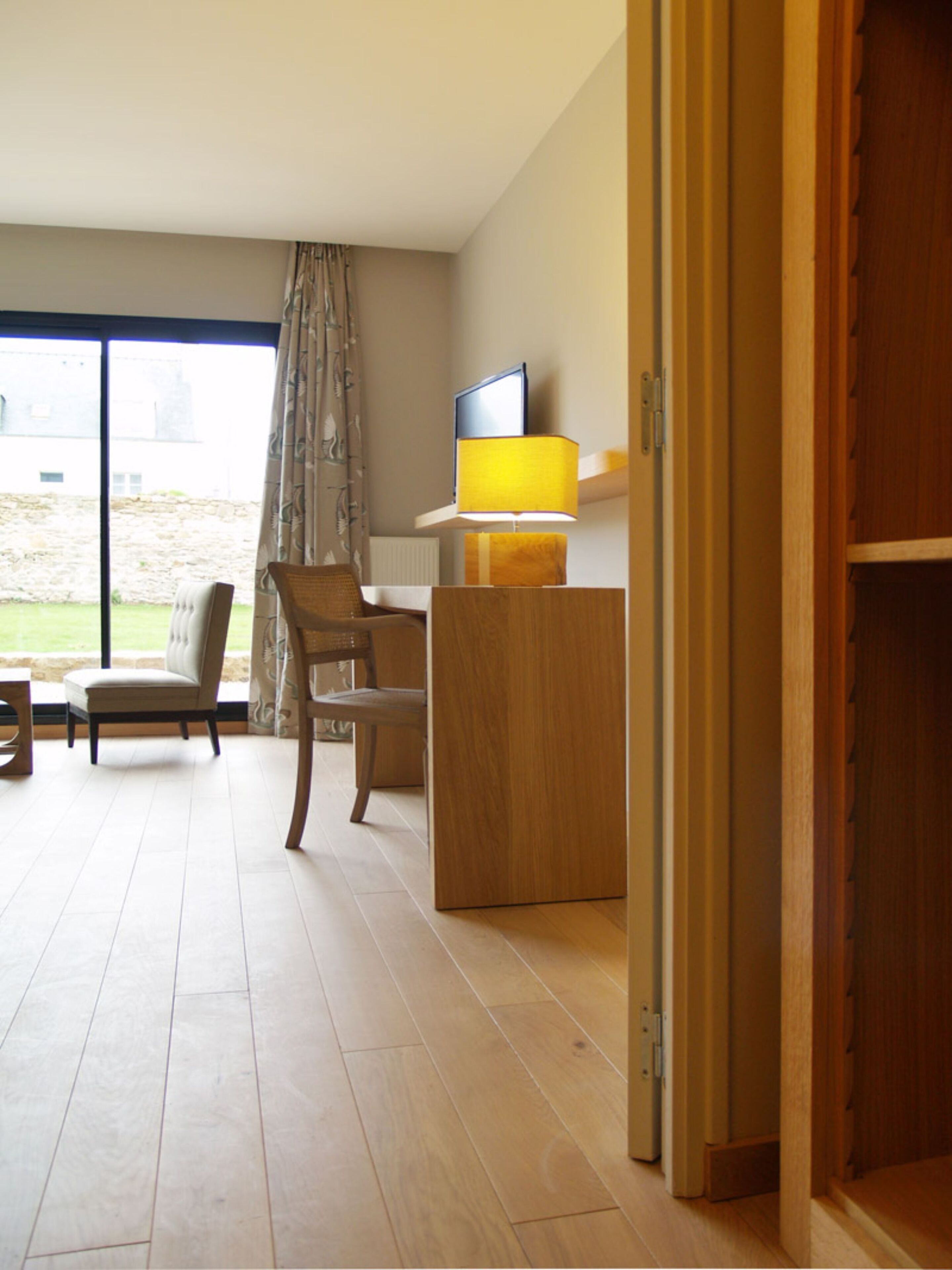 A room with a wooden desk, two chairs, a television, and a lamp.