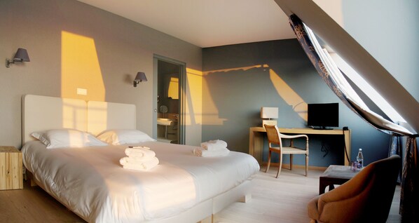 Una habitación de hotel con una cama grande, un escritorio, una silla y un televisor.