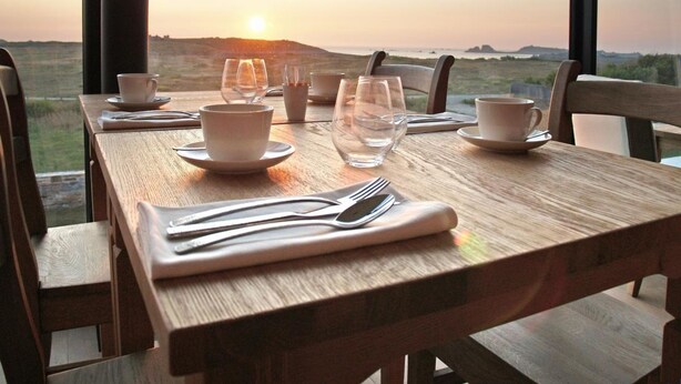 Mesa para dos lista, con vistas a la puesta de sol sobre el paisaje.