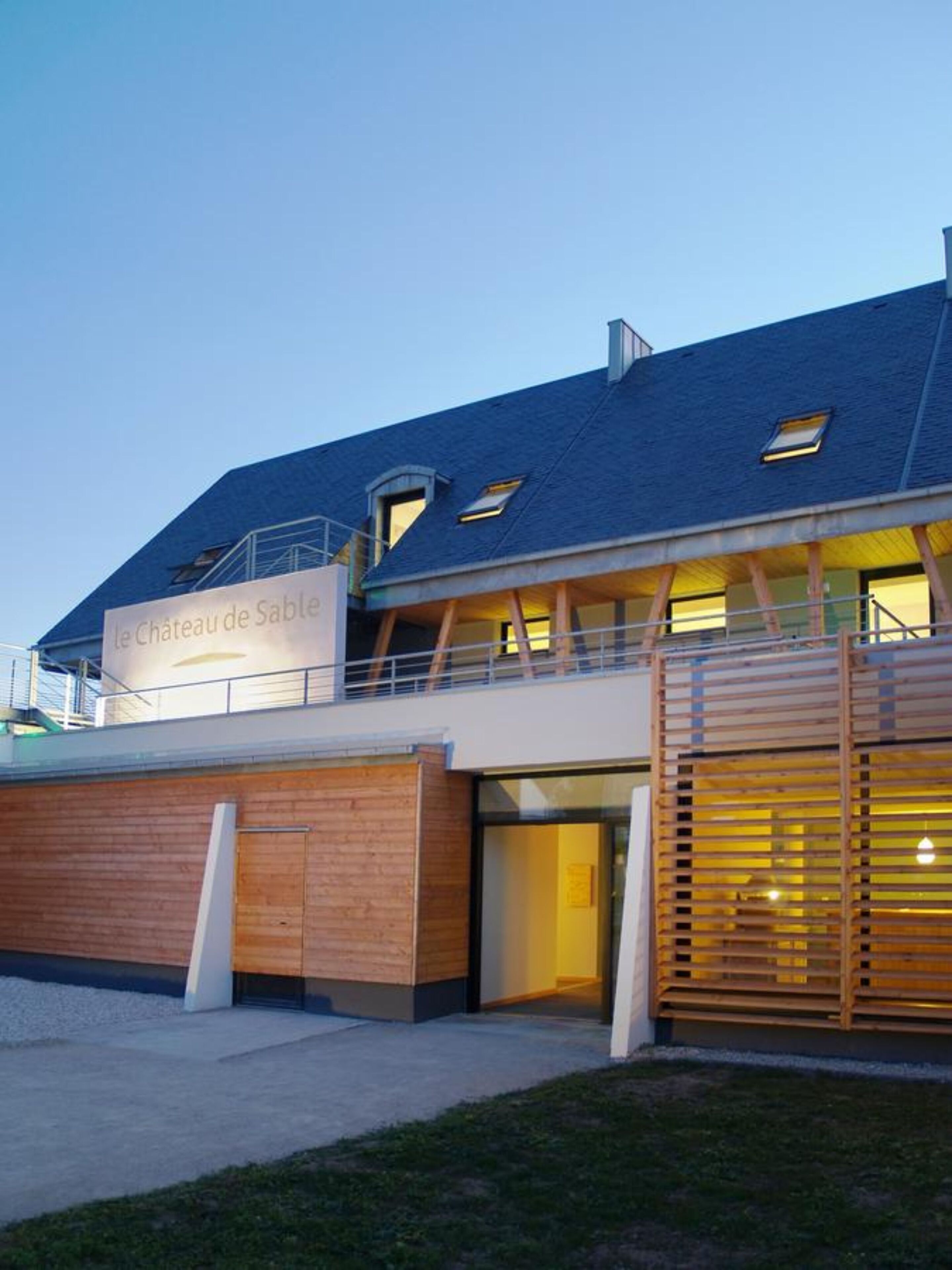 A modern building with a sign reading "Le Château de Sable".