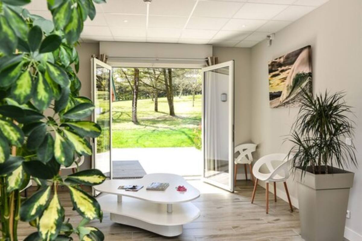 Una camera moderna con una porta in vetro che dà su un giardino, un tavolo bianco e una pianta in vaso.