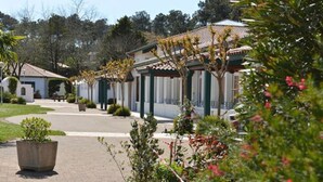 A courtyard with buildings, potted plants, and a pathway. - Domaine du Pignada (Anglet)