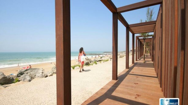 A wooden walkway leading to a beach with clear skies and calm waters. - Domaine du Pignada (Anglet)