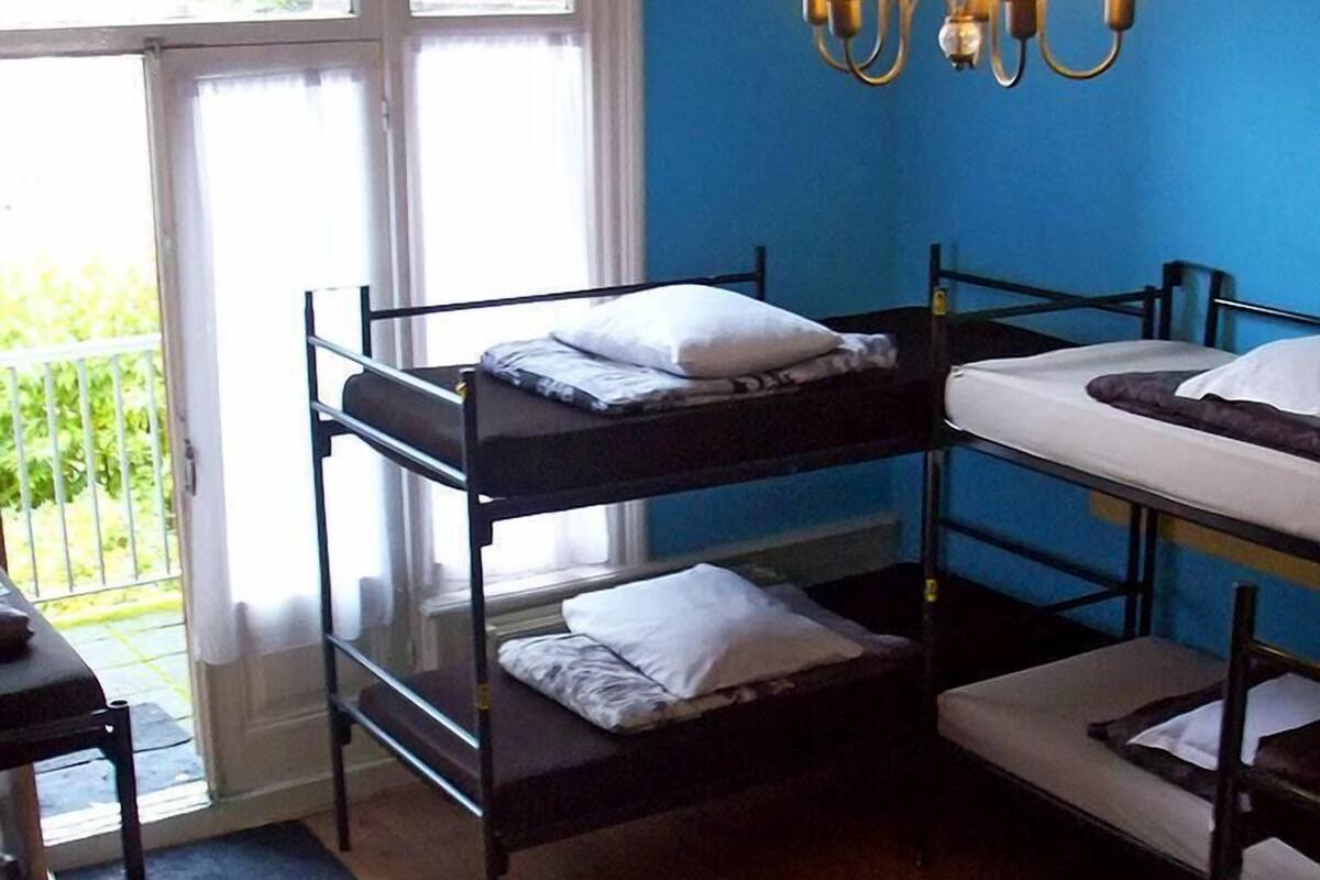 Ein Schlafsaalzimmer mit Etagenbetten, einem Balkon und einer Chandelüstere.