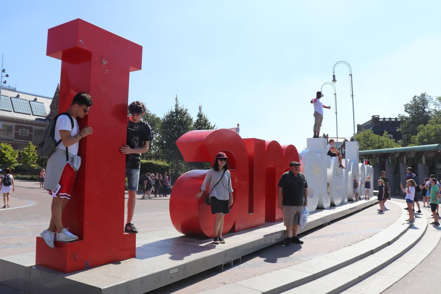A public space with large red letters spelling out a word, surrounded by people.