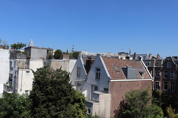 Un barrio residencial con varias edificaciones, incluyendo una casa blanca destacada con techo a dos aguas y una casa de ladrillo con techo de tejas rojas.