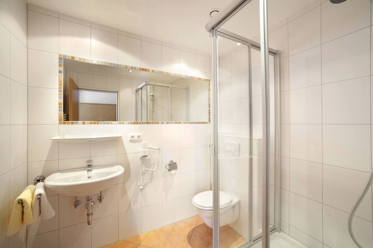 A bathroom with a glass-enclosed shower, a sink with a mirror above it, and a toilet.