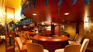 A bar area with a curved counter, orange upholstered chairs, and blue tinsel decorations. - Kneipp- Kur- und Tagungshotel Luitpold (Bad Woerishofen)