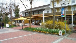 A cafe restaurant with outdoor seating and a flower bed in front. - Kneipp- Kur- und Tagungshotel Luitpold (Bad Woerishofen)