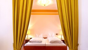 A hotel room with a bed, curtains, and a nightstand. - Kneipp- Kur- und Tagungshotel Luitpold (Bad Woerishofen)