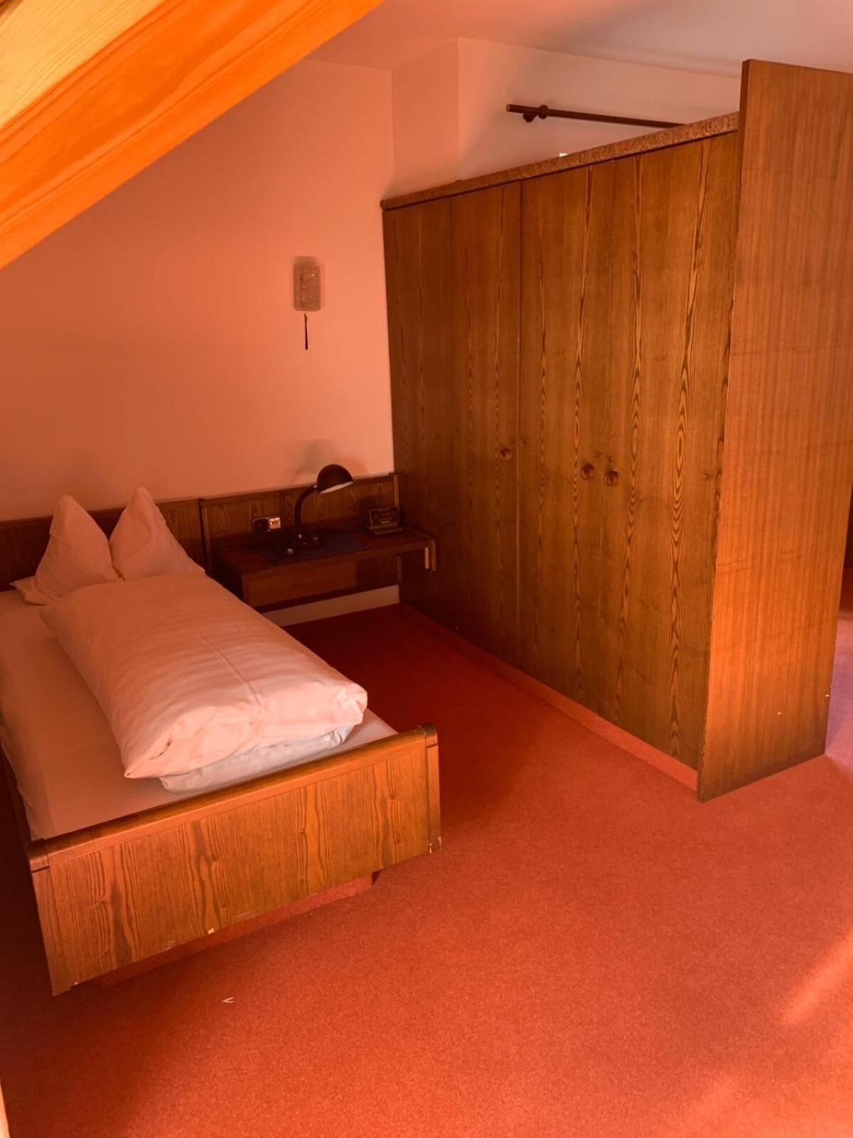 Ein Schlafzimmer mit einem hölzernen Bett, einem Nachttisch, einem Kleiderschrank und einem Deckenventilator.