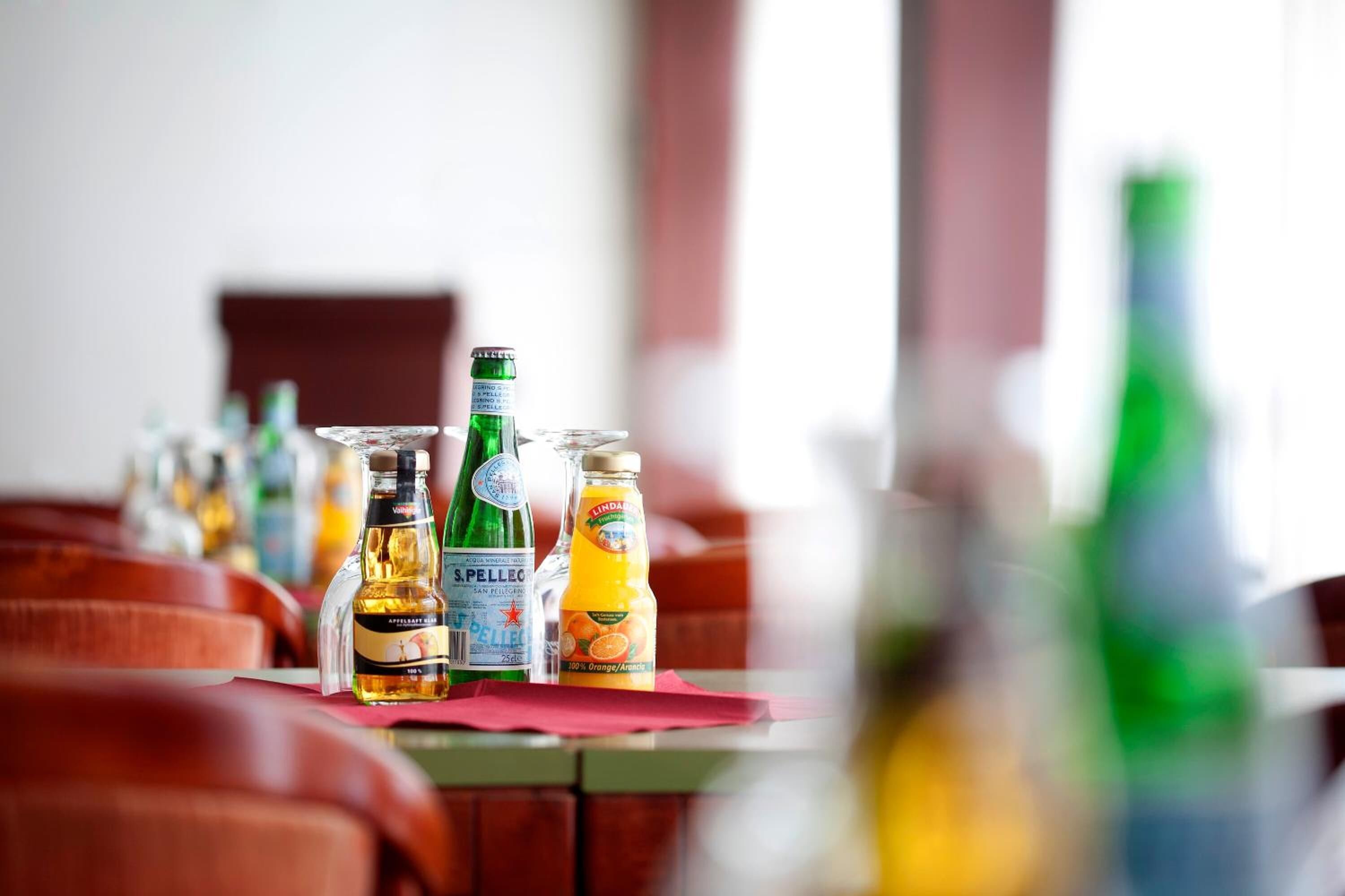 Filas de asientos rojos con cojines y botellas de bebidas sobre una mesa.