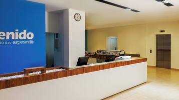 A reception desk with a blue wall, a clock, and an elevator.