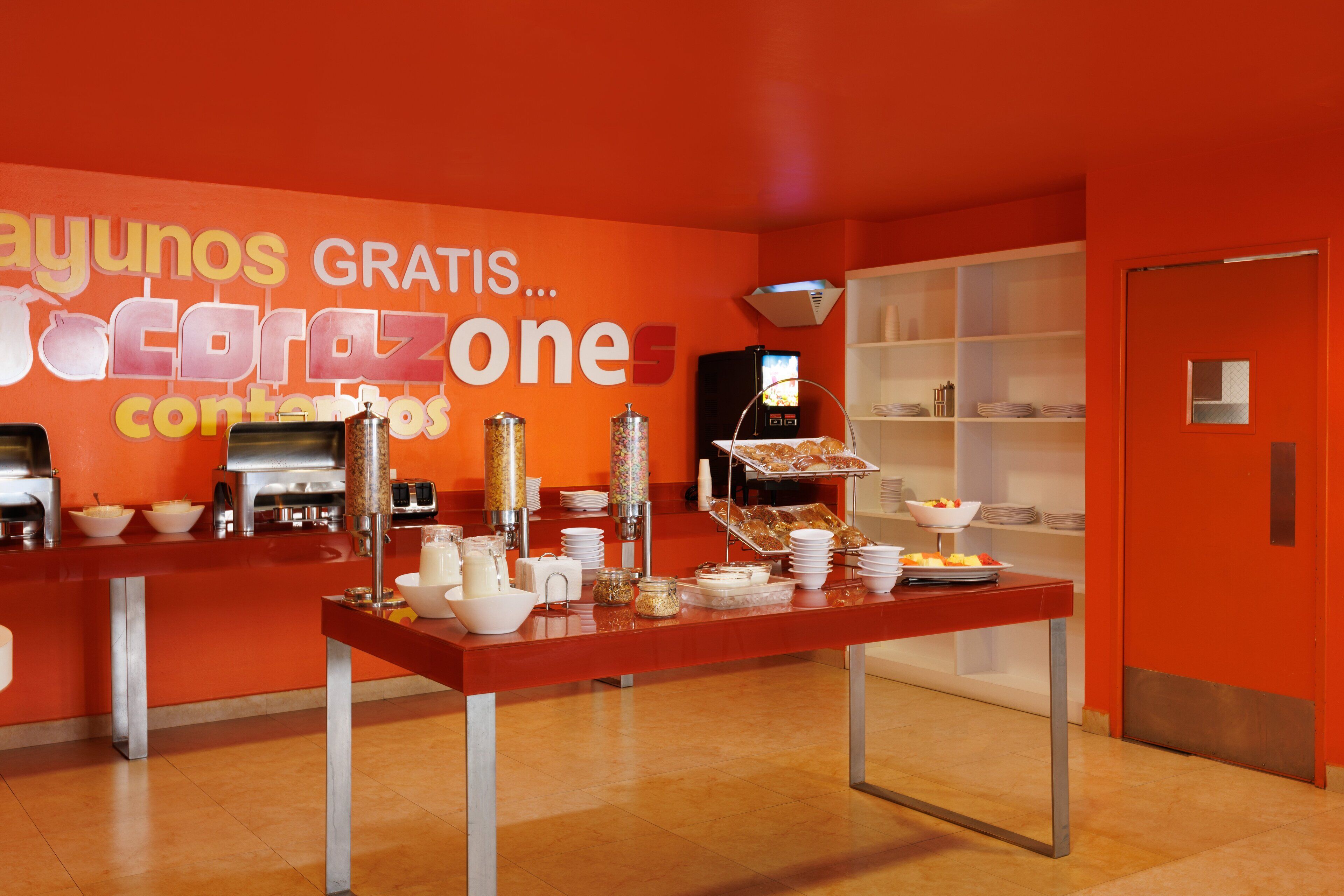 A buffet area with a red wall and a sign reading "ayuntos gratis...".