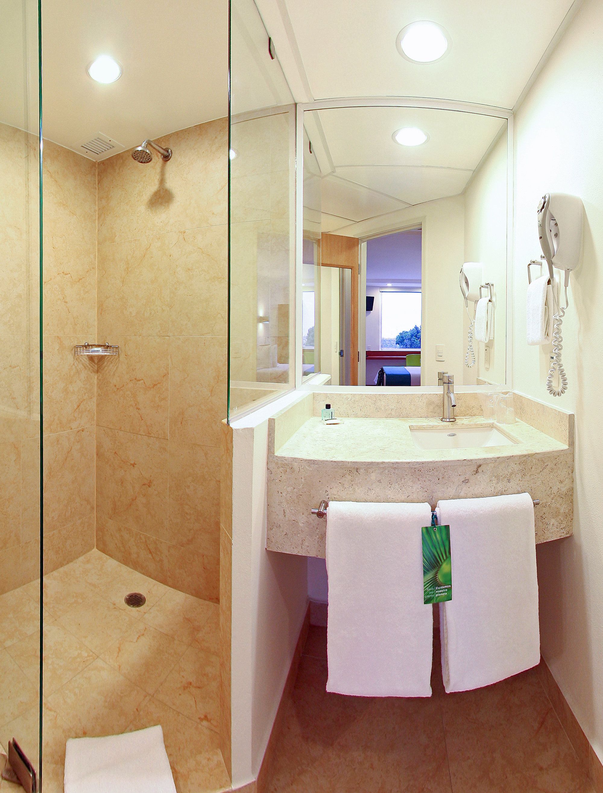 A modern bathroom with a glass-enclosed shower, a sink with a towel rack, and a mirror reflecting the room.