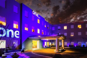 A hotel with a modern facade, multiple windows, and a well-lit entrance. - One Oaxaca Centro Hotel (Oaxaca)