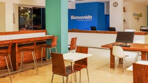 Zona de recepción con pared azul, mostrador de madera y varias sillas.